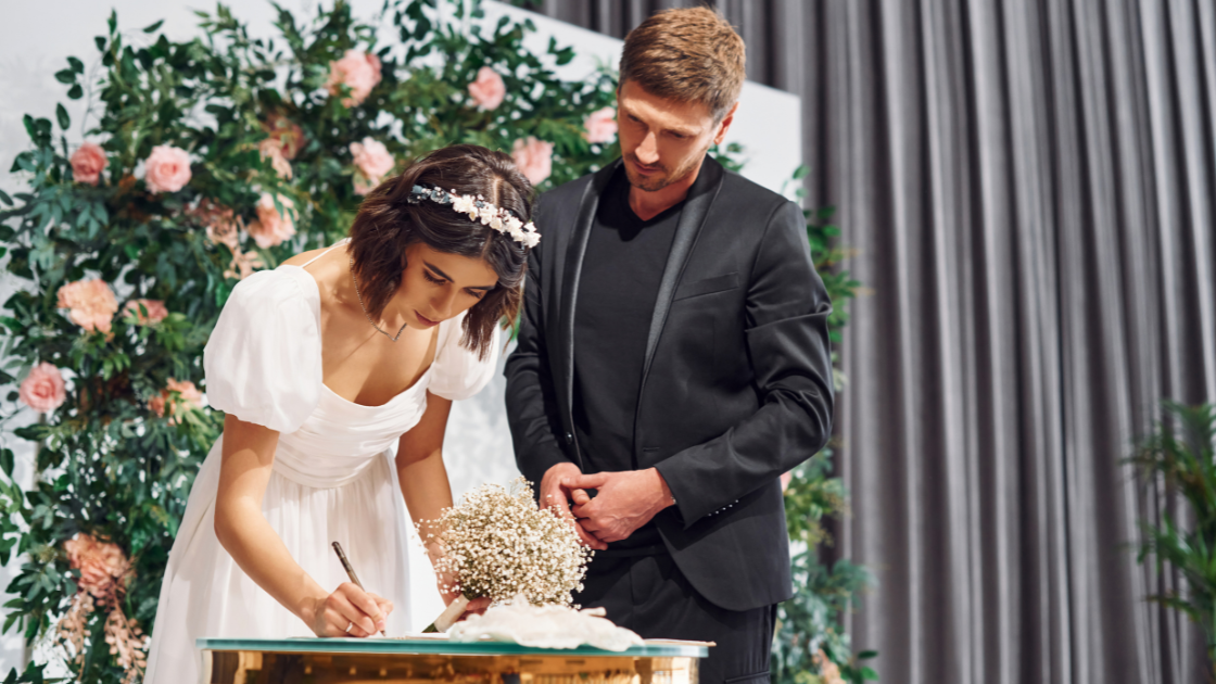 gorgeous white couple signing wedding insurance documents up on a stage